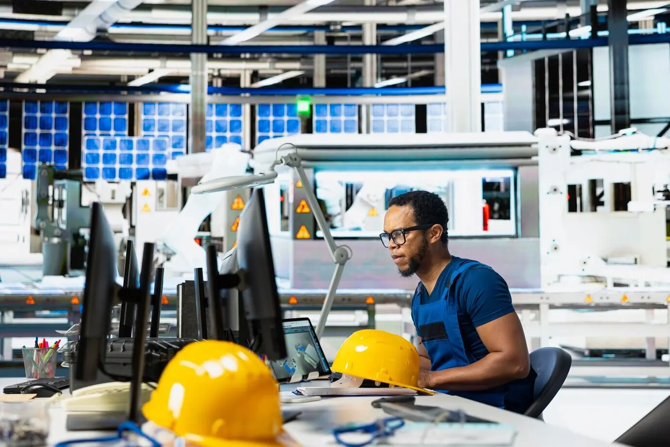 Ingeniero masculino utilizando un equipo informático para supervisar las líneas de ensamblaje de una planta de paneles solares